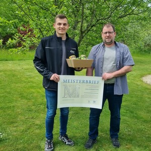 Lukas Schwarzfischer hält Meisterbrief in den Händen